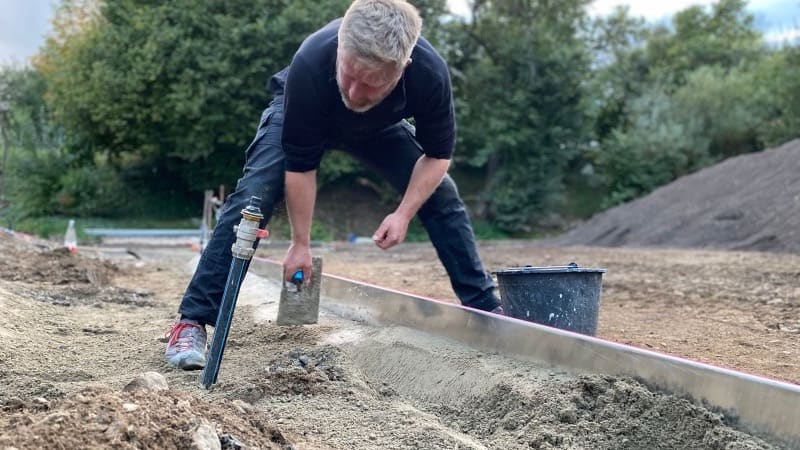 Landschaftsgärtner zieht eine Betonkante auf der Baustelle ab