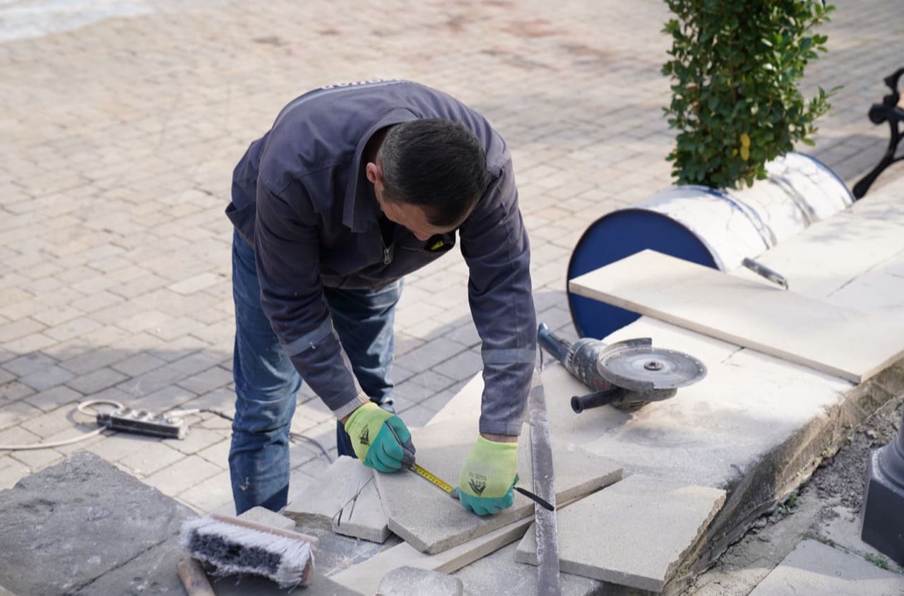 Fachkraft verlegt Platten für eine Terrasse im Garten