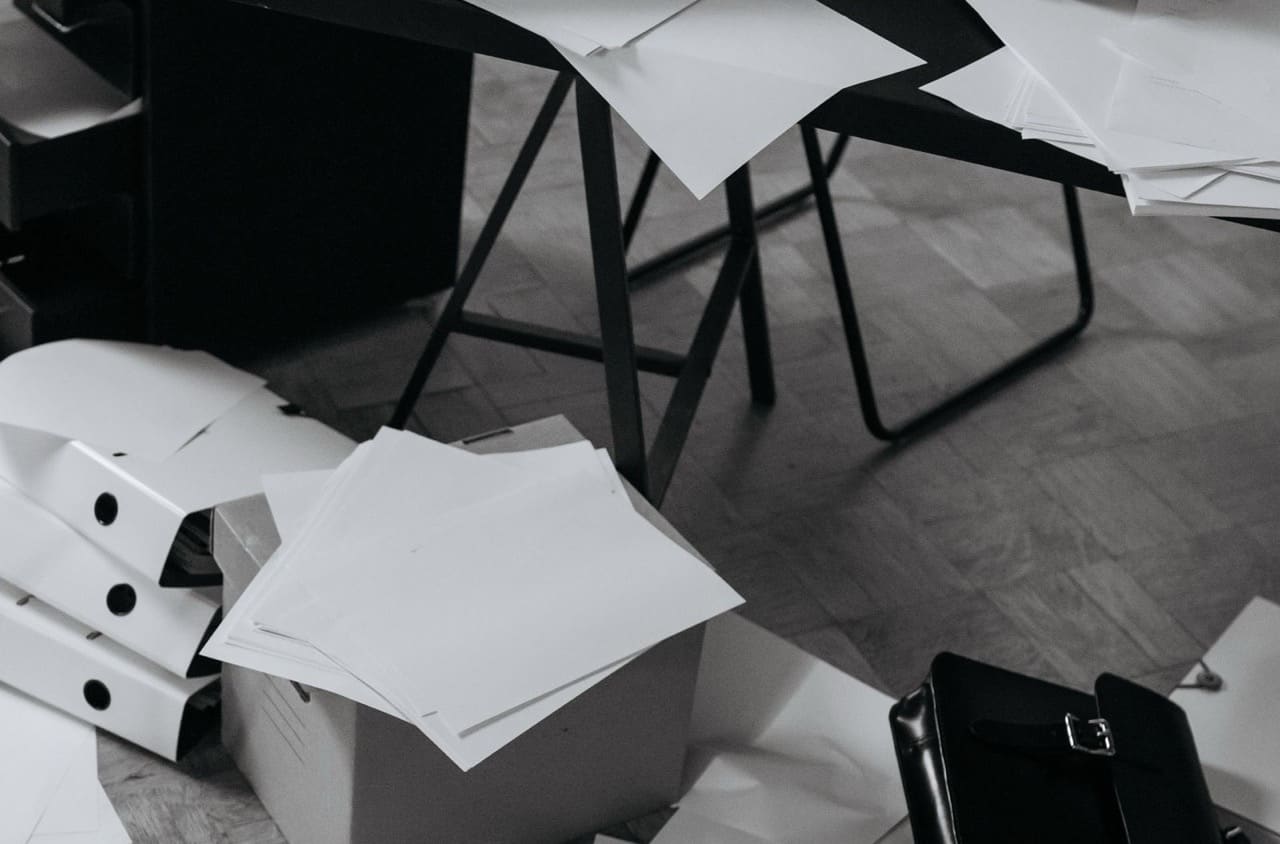 Schreibtisch mit verstreuten Unterlagen und Papieren