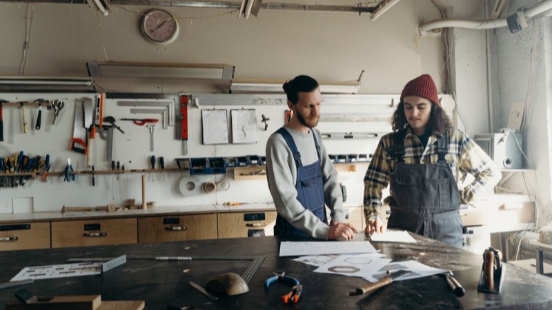 Zwei Handwerker besprechen Pläne an der Werkbank