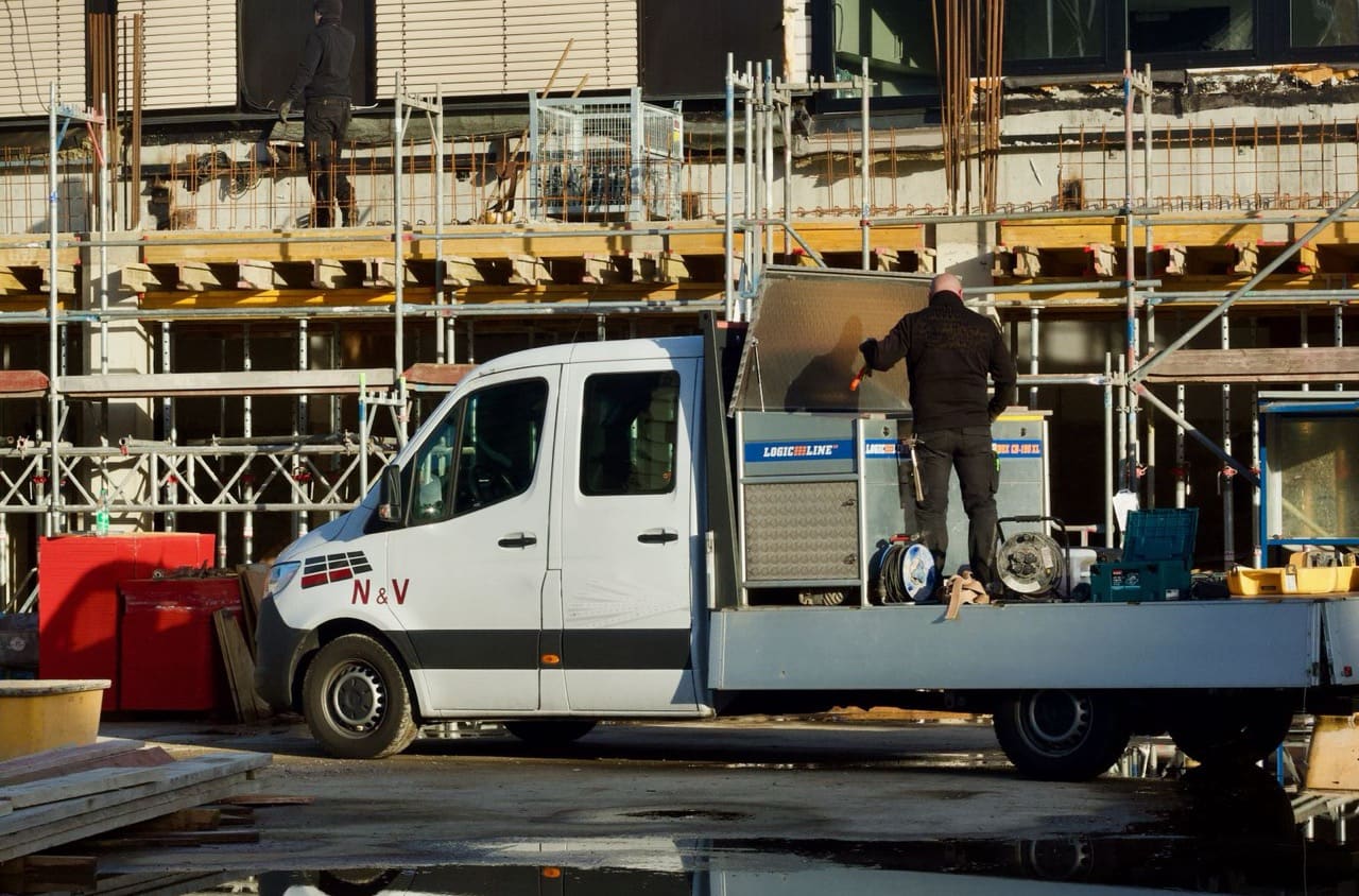 Handwerker mit Firmenfahrzeug auf der Baustelle